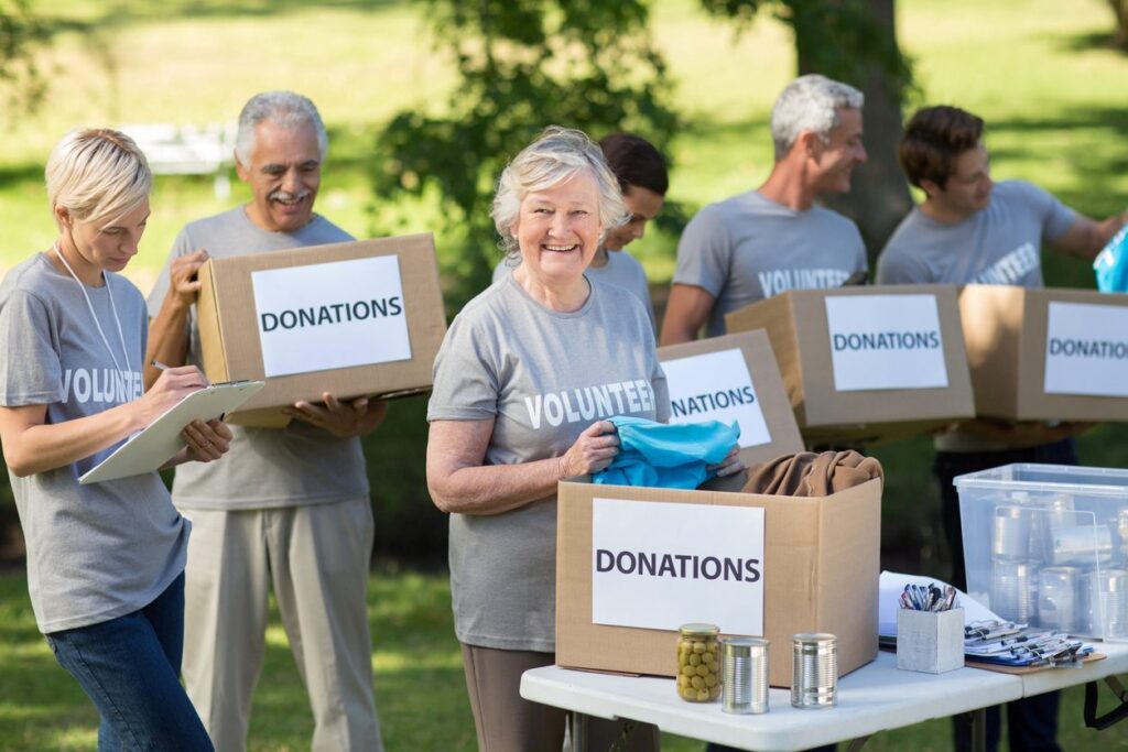 A group of smiling senior citizens helping with the collection of donation bins for charity.
